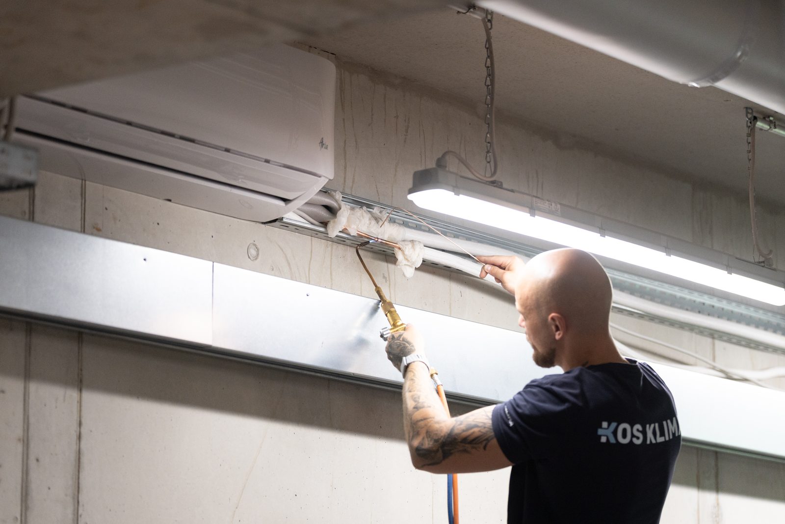KOS-KLIMA-Monteur bei Arbeiten an einem Deckengerät